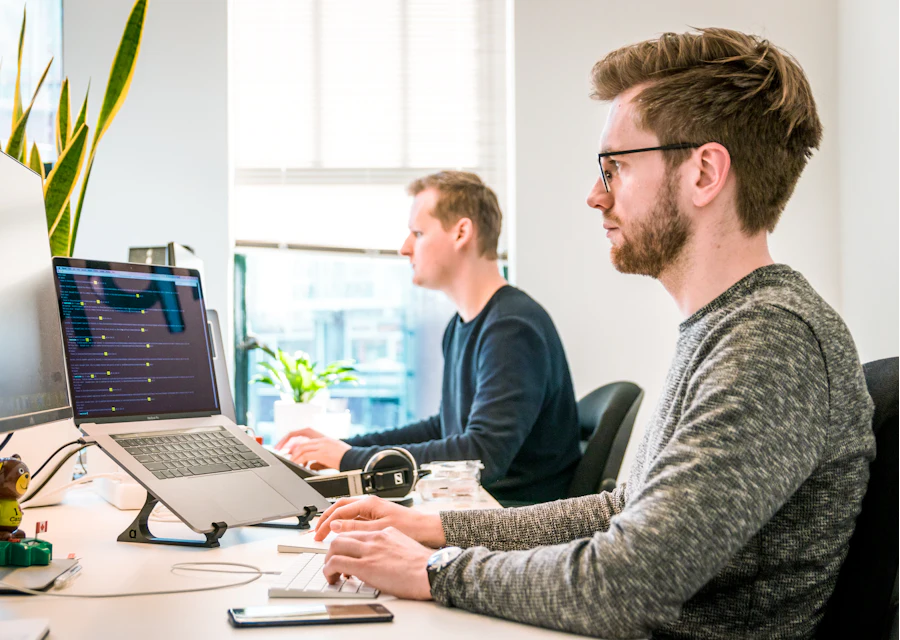 Zwei Entwickler arbeiten konzentriert an ihren Monitoren
