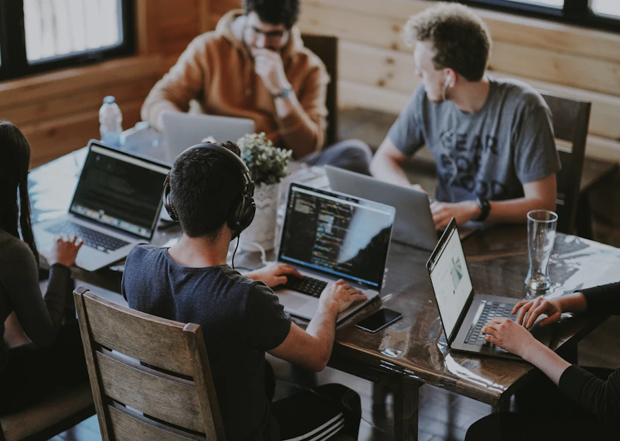 Entwicklerinnen und Entwickler arbeiten gemeinsam an Laptops